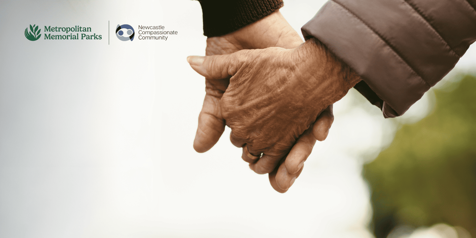 Two elderly hands gently clasping, conveying warmth and companionship. Logos for Metropolitan Memorial Parks and Newcastle Compassionate Community appear above.