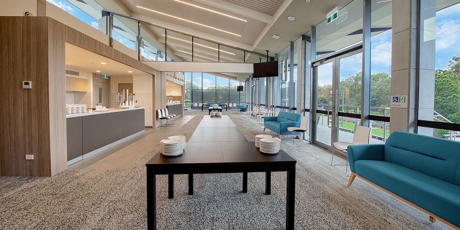 Spacious, modern interior of the Wallumatta Centre with a lounge area, a serving counter, and large windows overlooking greenery.