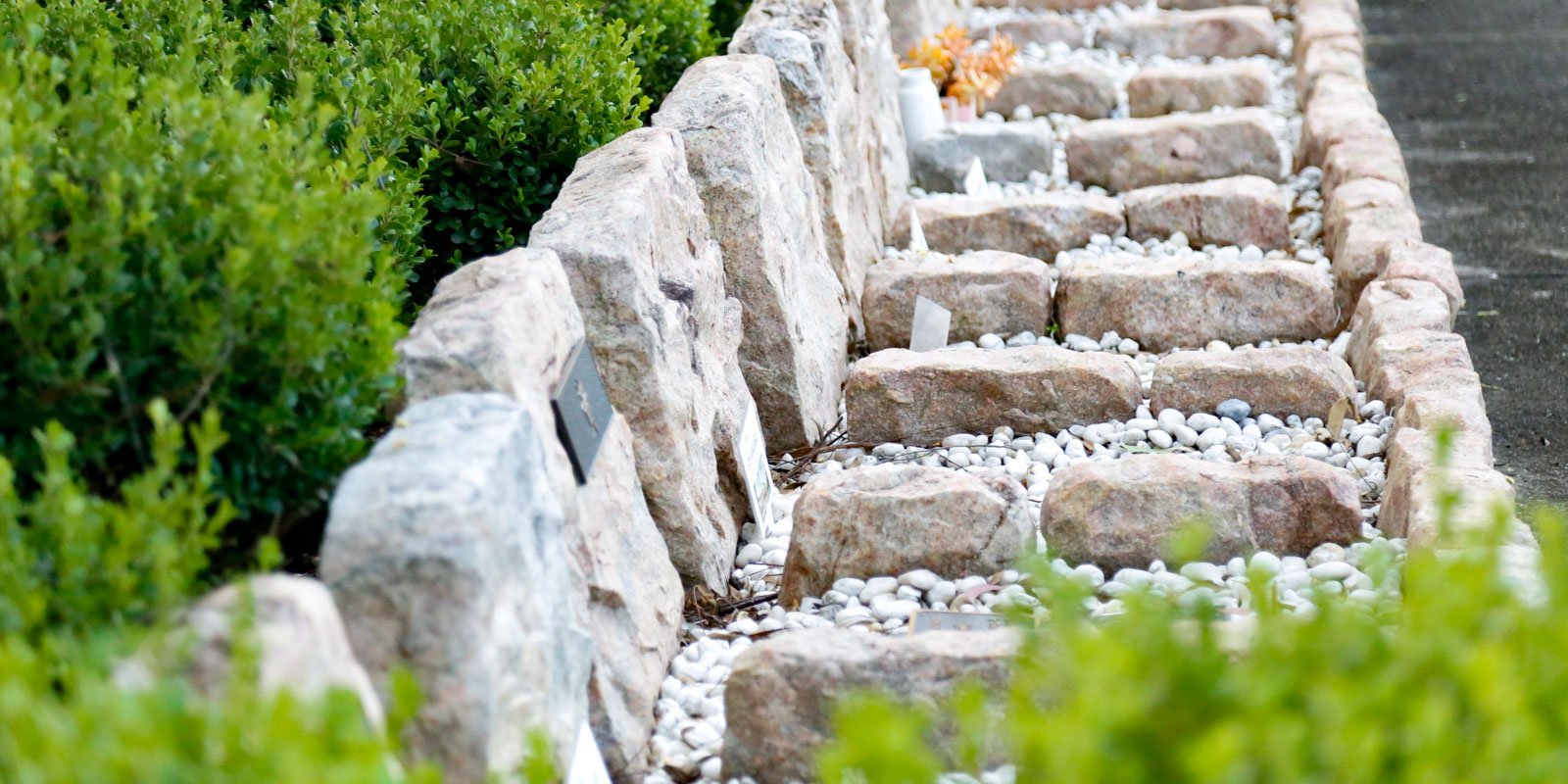 Green bushes line Continuous Rockeries at Rookwood Crematorium made natural stone.
