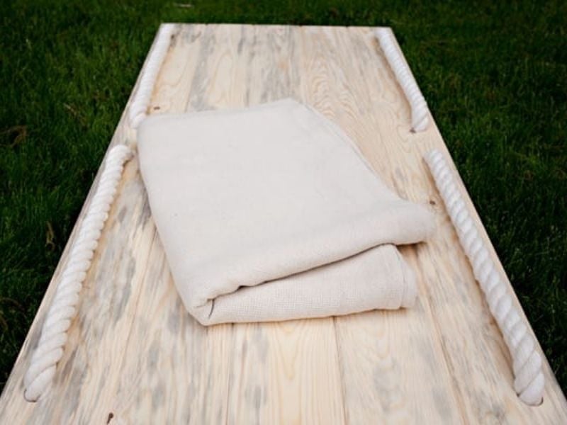 over top image of a shroud bearer, made of timber, with a folded square cloth sitting on top.