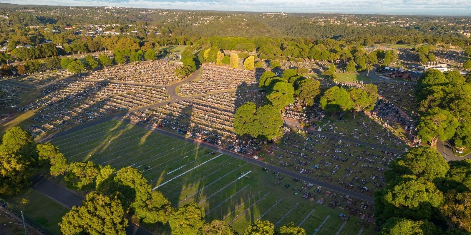 Aerial shot of Woronora Memorial Park with sun glaring down on a vast view of graves